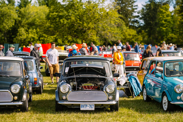 People walking around a car show outside.