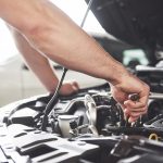 A photo of a mechanic working on the engine of a car.