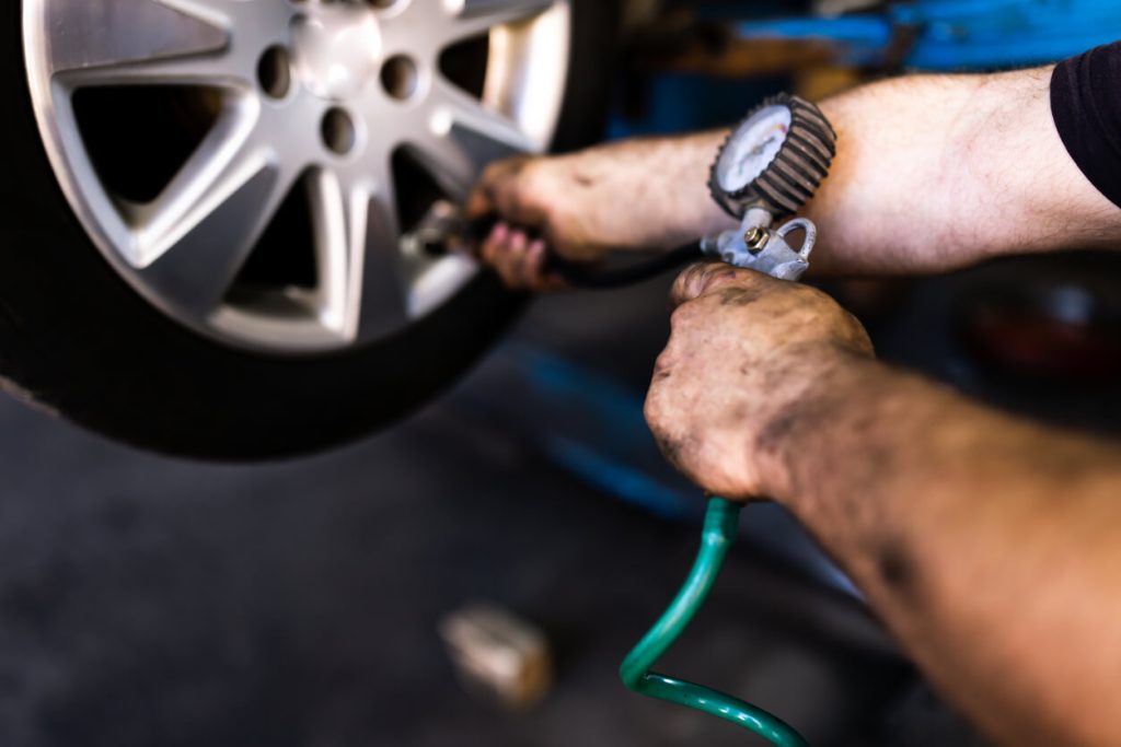 A photo of a man filling a car tire with air.