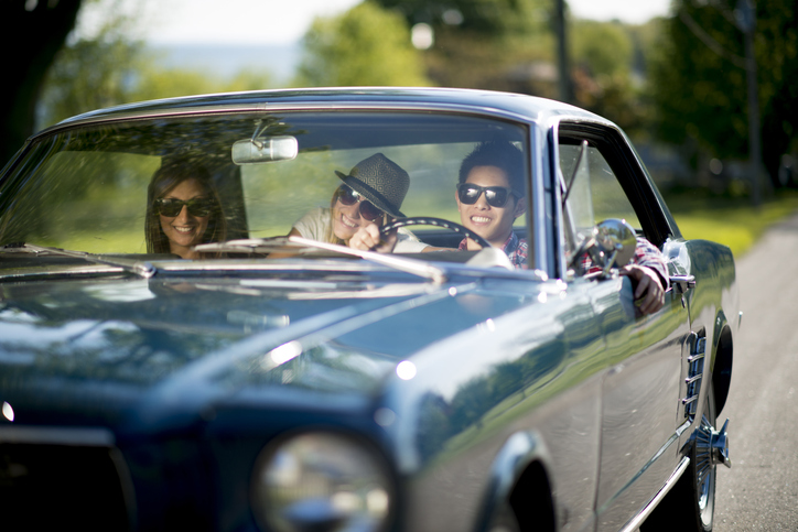 3 people on a road trip in a classic car.